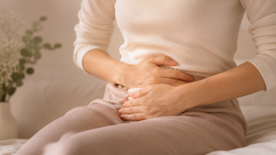 Mulher com as mãos no abdômen, representando dor pélvica associada à endometriose